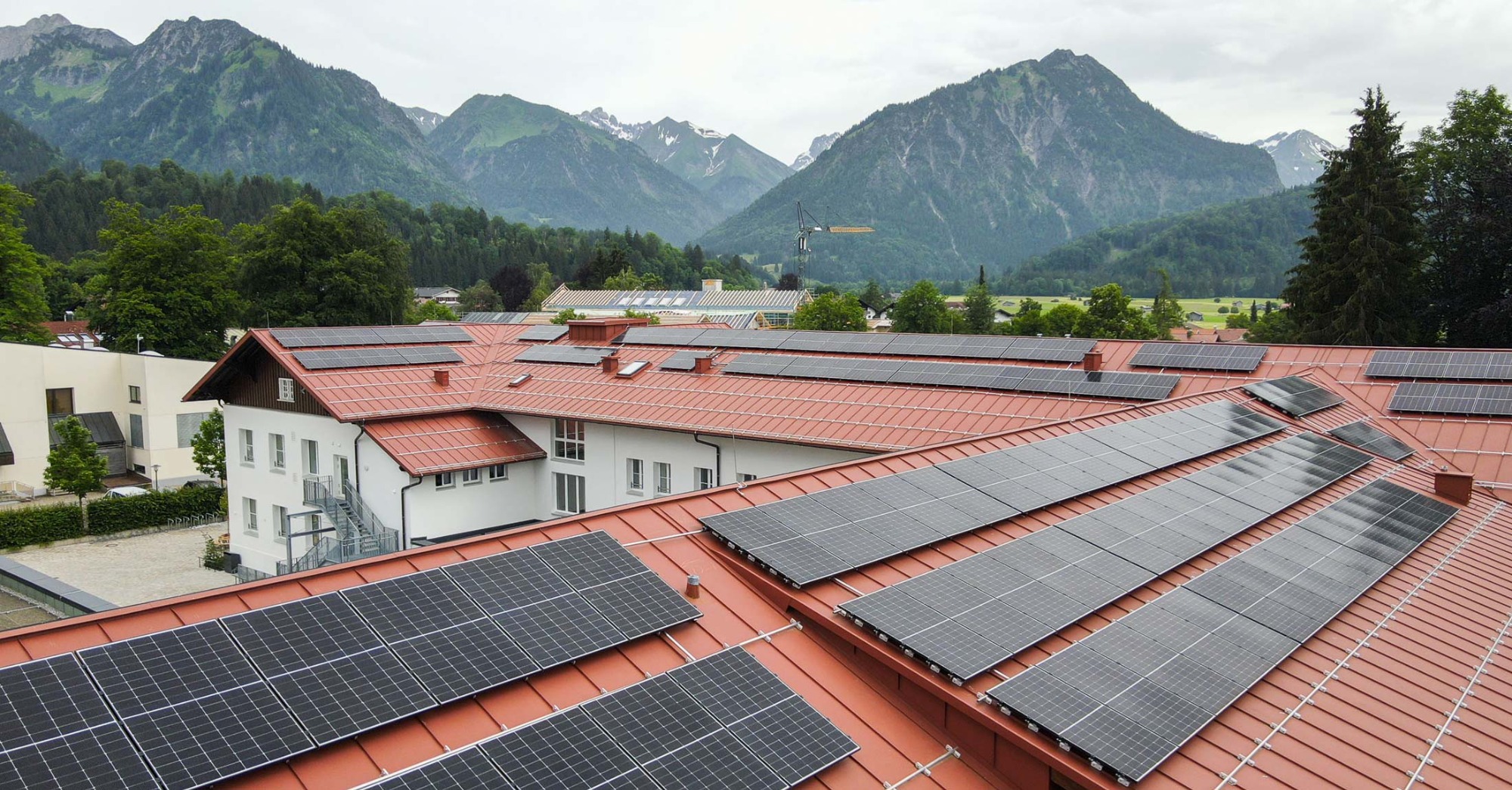 Photovoltaikanlage (PV) auf dem Dach der Grundschule Oberstdorf mit Bergen im Hintergrund